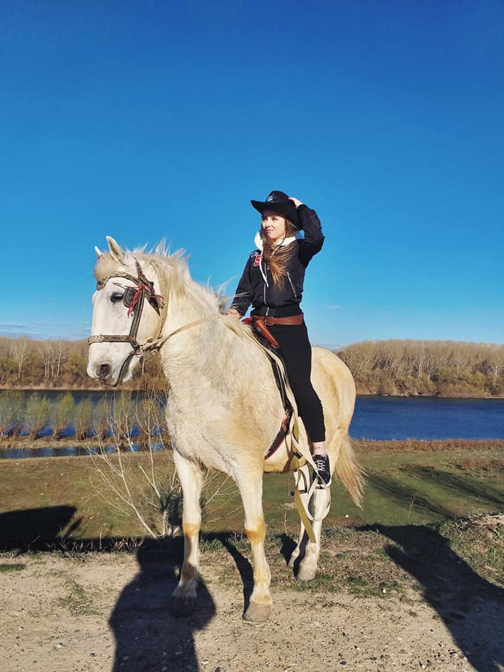 Participant călare pe un cal alb într-o activitate de teambuilding cu tematică de aventură și curaj